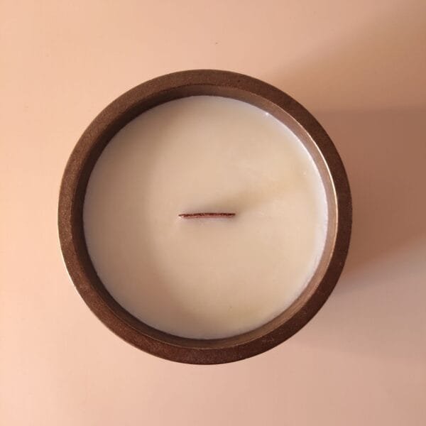 Bougie Cacao Alchimie Métallique - vue de dessus montrant la mèche en bois et la cire, fond marbre beige